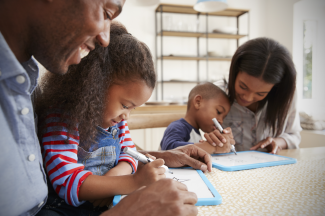 Père et mère qui dessinent avec leurs deux enfants.
