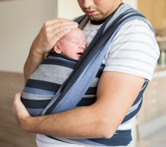 Père qui porte son nouveau-né dans une écharpe de portage Père qui porte son nouveau-né dans une écharpe de portage