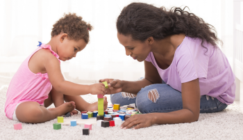 Une mère et sa fille font une tour avec des blocs en bois.
