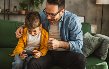 Un père et son enfant s’amusent sur un jeu vidéo mobile Un père et son enfant s’amusent sur un jeu vidéo mobile