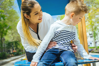 Petit garçon au parc qui refuse de faire ce que sa mère lui demande Petit garçon au parc qui refuse de faire ce que sa mère lui demande