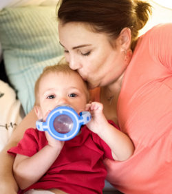 Enfant qui boit son lait dans un verre à bec avec sa mère
